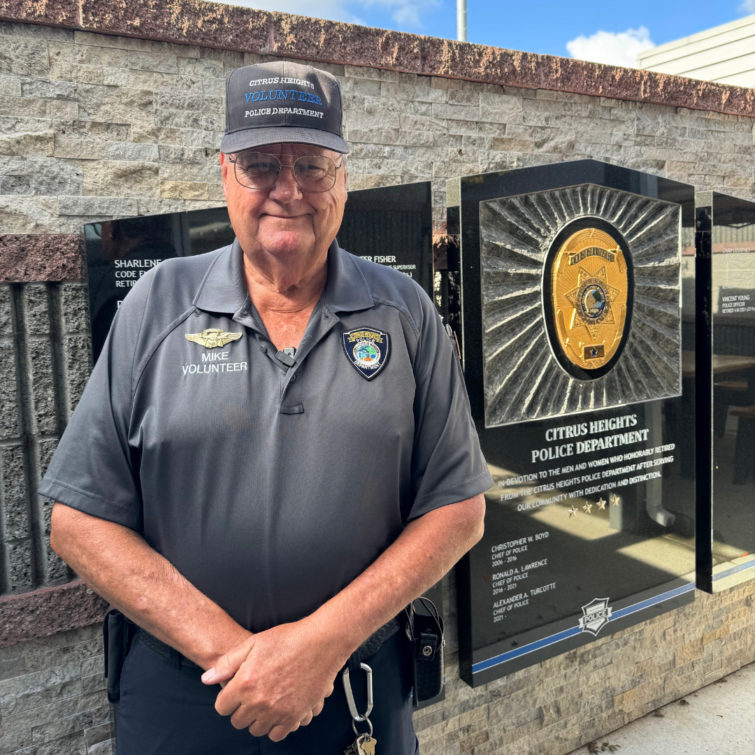 Mike stands in front of a Citrus Heights Police plaque with his hands crossed in front of him.