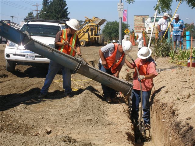 Construction workers pouring concrete into a trench