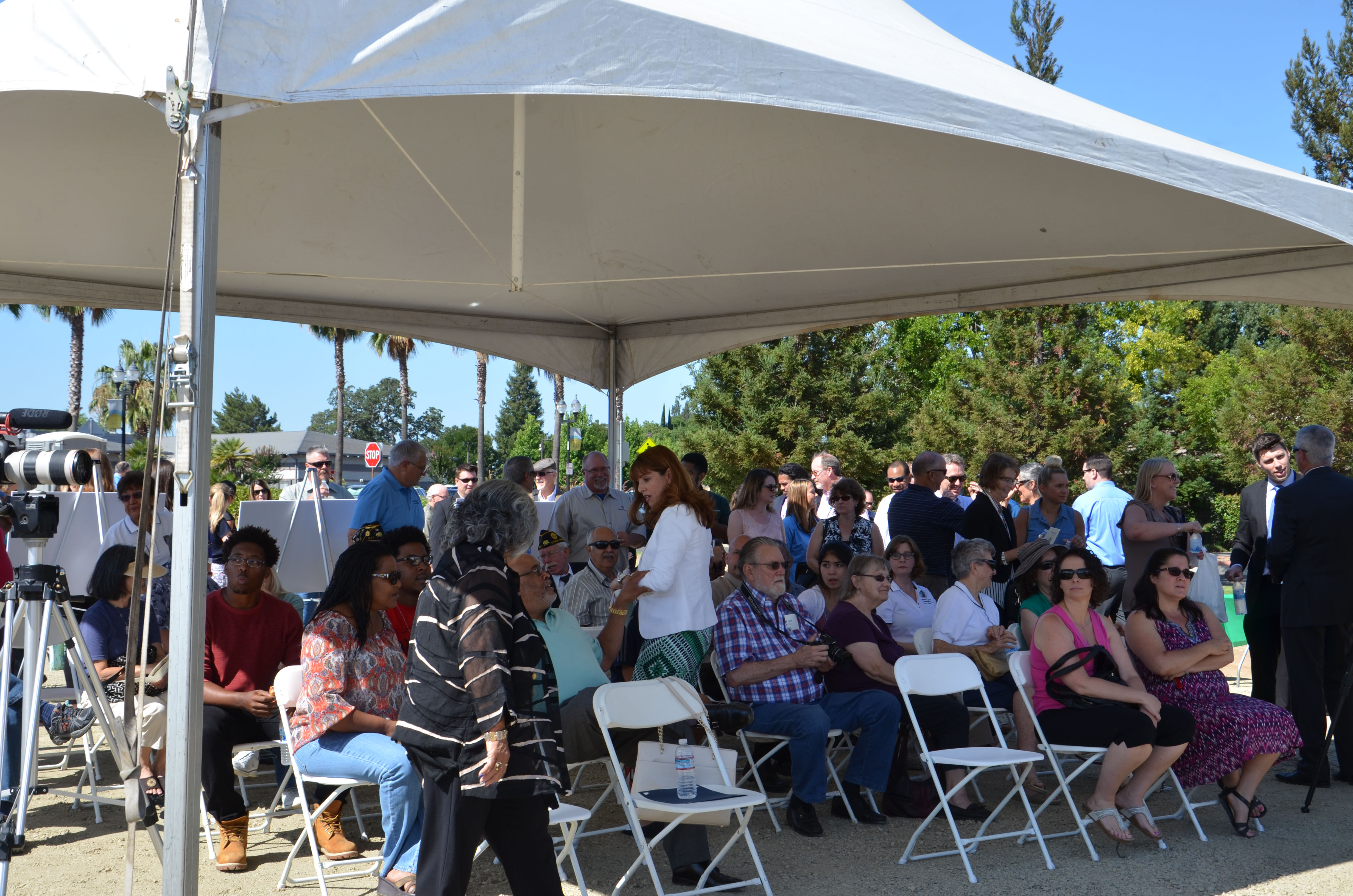 The community gathers under a tent for the ceremony